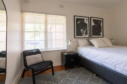 a bedroom with a bed and a chair in it at Gem Apartment 4 - Courtyard I Beach I Wifi I Cafes in Glenelg