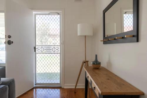 a living room with a mirror and a table at Gem Apartment 4 - Courtyard I Beach I Wifi I Cafes in Glenelg