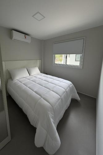 a large white bed in a room with a window at Studio47 - Compact, equipped and well located in Itajaí