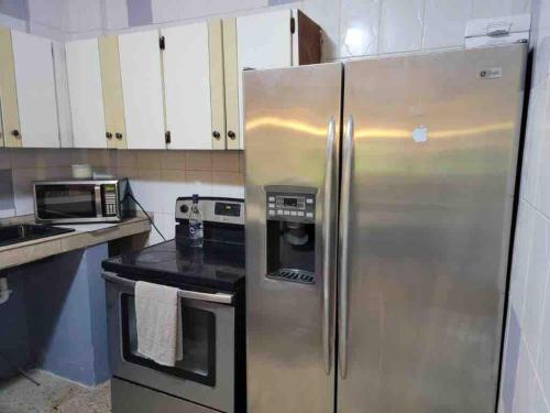 Una cocina con refrigerador de acero inoxidable y microondas. en La marquesina guess home, en Loiza