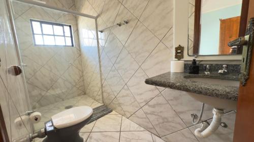 a bathroom with a shower and a toilet and a sink at Nova Aliança Suítes por Temporada em Amparo NÃO SOMOS POUSADA in Amparo