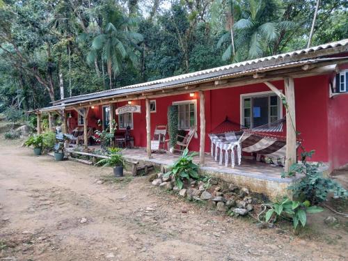 a red house with a hammock outside of it at Canto da Cachoeira relaxe ao som das águas in Tijucas