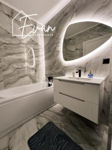 a bathroom with a sink and a tub and a mirror at Luxury Park View Apartment by Evan Apartments in Şelimbăr