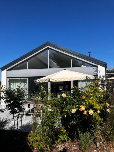 a white house with an umbrella and some flowers at Villa Botanica in Odargowo