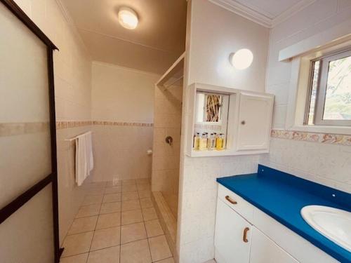 een witte badkamer met een wastafel en een spiegel bij Maree's Beachfront House - Free Internet in Arorangi