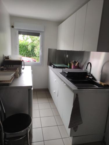 eine Küche mit weißen Schränken und einer Spüle und einem Fenster in der Unterkunft chambre plan d eau in Saint-Biez-en-Belin