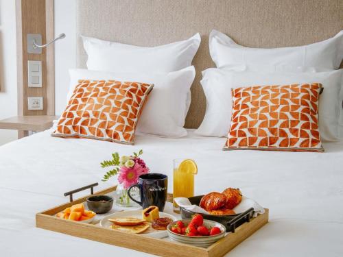 a tray of fruit and breakfast on a bed at Novotel Lyon Centre-Confluence Bord de Saone in Lyon