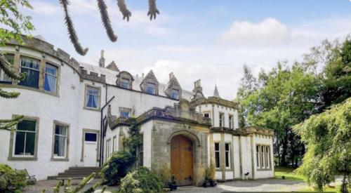 an old house with a wooden door in a yard at Harvieston Estate Rooms in Gorebridge