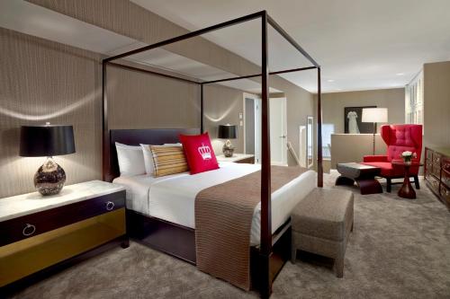 a bedroom with a canopy bed and a red chair at The Omni King Edward Hotel in Toronto
