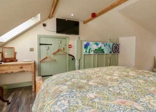 a bedroom with a bed and a desk and a television at Seaglass Cottage in Flamborough
