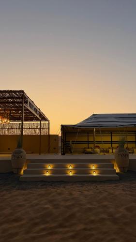 a group of tables with lights in front of a building at FYAFY Bidiyah Bedouin Camp in Badīyah