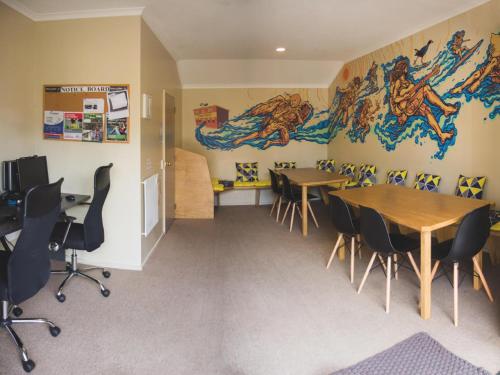 a room with two tables and chairs and a mural at The Prince Albert Backpackers & Bar in Nelson