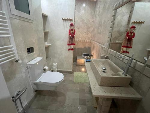 a bathroom with a toilet and a sink and two dolls at Résidence Mila in La Soukra