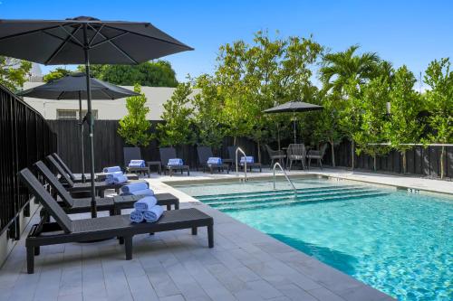 a swimming pool with chairs and umbrellas next to a pool at Prestige Retreat by Renzzi in Miami