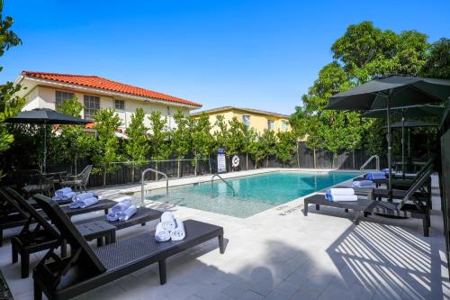a swimming pool with tables and umbrellas next to a building at Prestige Retreat by Renzzi in Miami