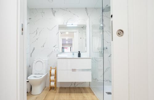 une salle de bains blanche avec toilettes et lavabo dans l'établissement Stay U-nique Apartments Albeniz BCN, à L'Hospitalet de Llobregat