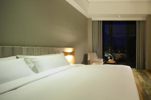 a bedroom with a large white bed and a window at South Urban Hotel in Chiayi City