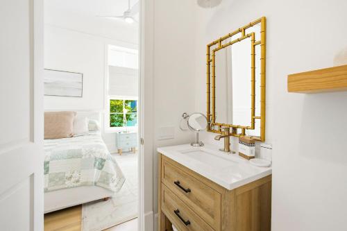 une salle de bain avec un lavabo et un miroir à côté d'un lit dans l'établissement Barefoot Bungalow by Stay on 30a, à Seagrove Beach