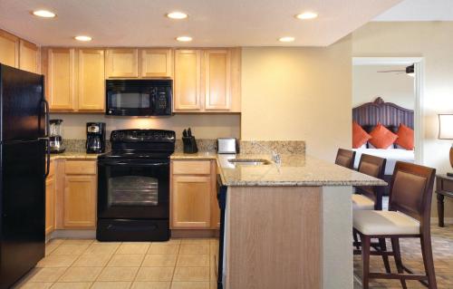 a kitchen with wooden cabinets and a black refrigerator at Club Wyndham Palm-Aire in Pompano Beach