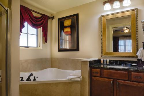 een badkamer met een bad, een wastafel en een spiegel bij Club Wyndham La Cascada in San Antonio