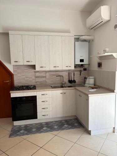 a kitchen with white cabinets and a sink and a stove at Amber house in Lesina