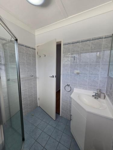 ein weißes Badezimmer mit Waschbecken und Dusche in der Unterkunft Hydra 2 bedroom Holiday Unit in Merimbula