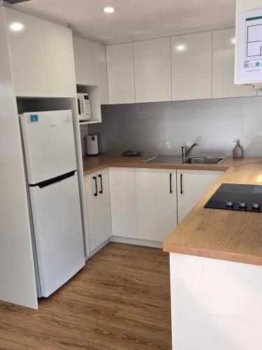 a kitchen with white cabinets and a white refrigerator at Hydra 2 bedroom Holiday Unit in Merimbula