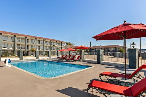 a pool with chairs and umbrellas next to a building at HomeTowne Studios by Red Roof San Antonio E - Frost Bank Center in San Antonio