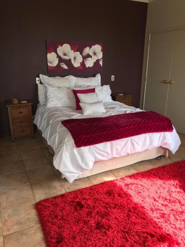 a bedroom with a large bed with a red rug at Harbour views in Athenree