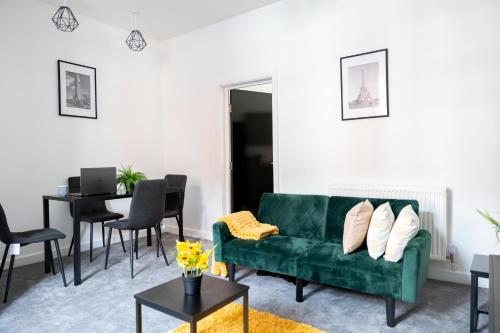 een woonkamer met een groene bank en een tafel bij Stylish 3-Bed 15min to Manchester City Centre in Ashton under Lyne