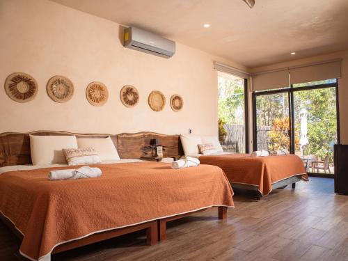 1 Schlafzimmer mit 2 Betten und orangefarbener Bettwäsche in der Unterkunft Villas Mandarina Bacalar in Bacalar