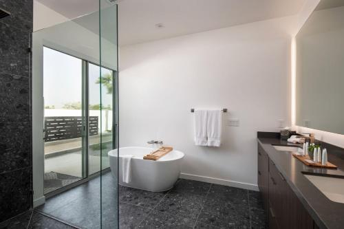 a bathroom with a tub and a glass shower at Carbon @ Elemento49 Pool Spa Sleeps 16 in Desert Groves Mobile Home Park