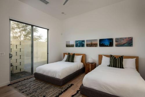 two beds in a room with a window at Carbon @ Elemento49 Pool Spa Sleeps 16 in Desert Groves Mobile Home Park