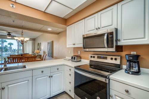 HP 124 Condo by 30A Escapes في روزماري بيتش: مطبخ مع دواليب بيضاء وميكرويف