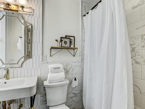 a white bathroom with a shower curtain and a sink at Gordon Inn Holly in Savannah