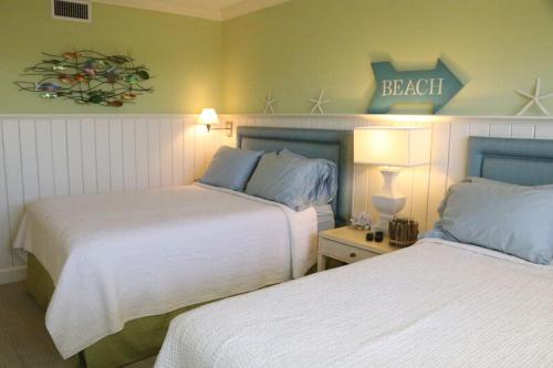 シエスタ・キーにあるGulf and Bay Club- F503のベッド2台が備わる客室で、壁に看板が付いています。