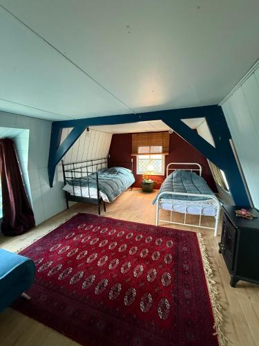 an attic bedroom with two beds and a red rug at Indigena Forest Retreat -Entire 6 persons Family home near Efteling and Dunes in Sprang-Capelle
