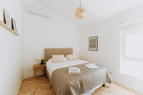 ein weißes Schlafzimmer mit einem Bett mit zwei Handtüchern darauf in der Unterkunft Boutique Apartments Old Town in Mostar