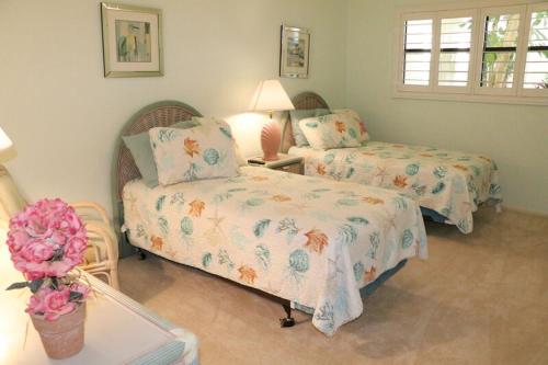 a bedroom with two beds and a table with a lamp at Gulf and Bay Club- F105 in Siesta Key
