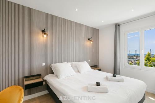 a bedroom with a large white bed and a window at Azurenting - vue sur le port - roof top 3 in Vallauris