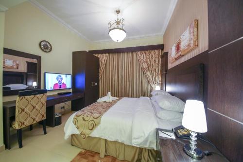 a hotel room with a bed and a television at Ivory Grand Hotel Apartments in Dubai