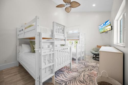 a white bedroom with two bunk beds and a desk at Lemon Bay Luxe – Dock, Beach & Manasota Vibes in Punta Gorda Beach