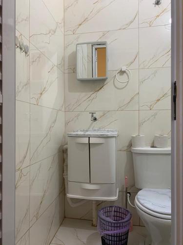 a bathroom with a toilet and a mirror on the wall at Pousada Fênix,com piscina -250 METROS DA PRAIA in Pontal do Paraná