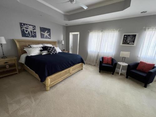 a bedroom with a large bed and two chairs at Manasota Key Gem - Pool and Hot Tub - Beach Views in Punta Gorda Beach