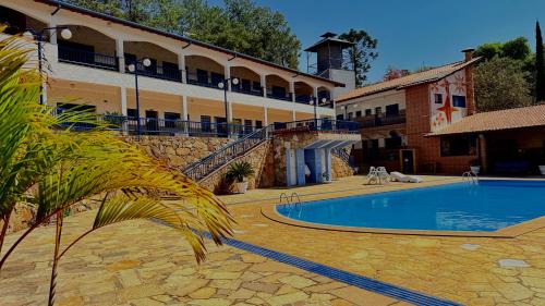 a hotel with a swimming pool in front of a building at Nova Aliança Suítes por Temporada em Amparo NÃO SOMOS POUSADA in Amparo