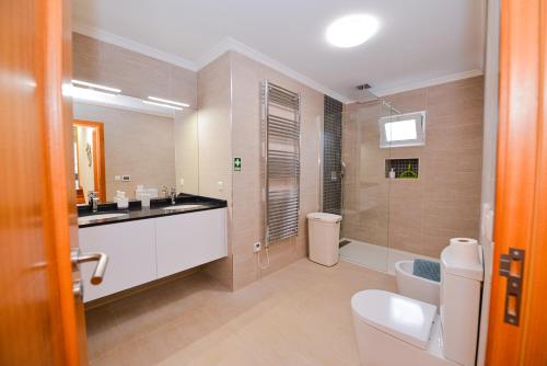 a bathroom with a sink and a toilet and a shower at Casa do Cantinho do Muro in São Vicente