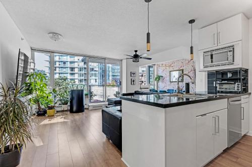 a kitchen with white cabinets and a large window at Gastown Downtown Apartment very central in Vancouver