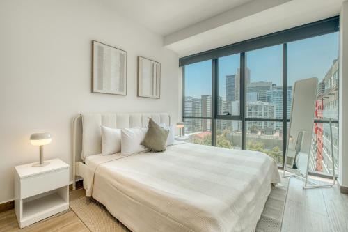 ein Schlafzimmer mit einem großen Bett und einem großen Fenster in der Unterkunft Nido at Gran Ciudad Nuevo Polanco in Mexiko-Stadt
