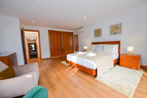 a bedroom with a large bed and a couch at Casa do Cantinho do Muro in São Vicente