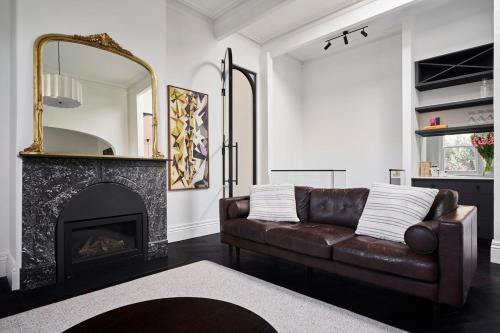a living room with a leather couch and a fireplace at Bendigo Signature Accommodation Wattle Street in Bendigo